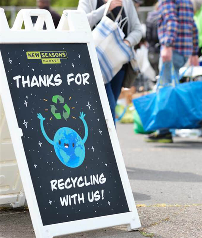 a sign at an outdoor recycling event that says "thanks for recycling with me" and features an illustration of the planet earth.