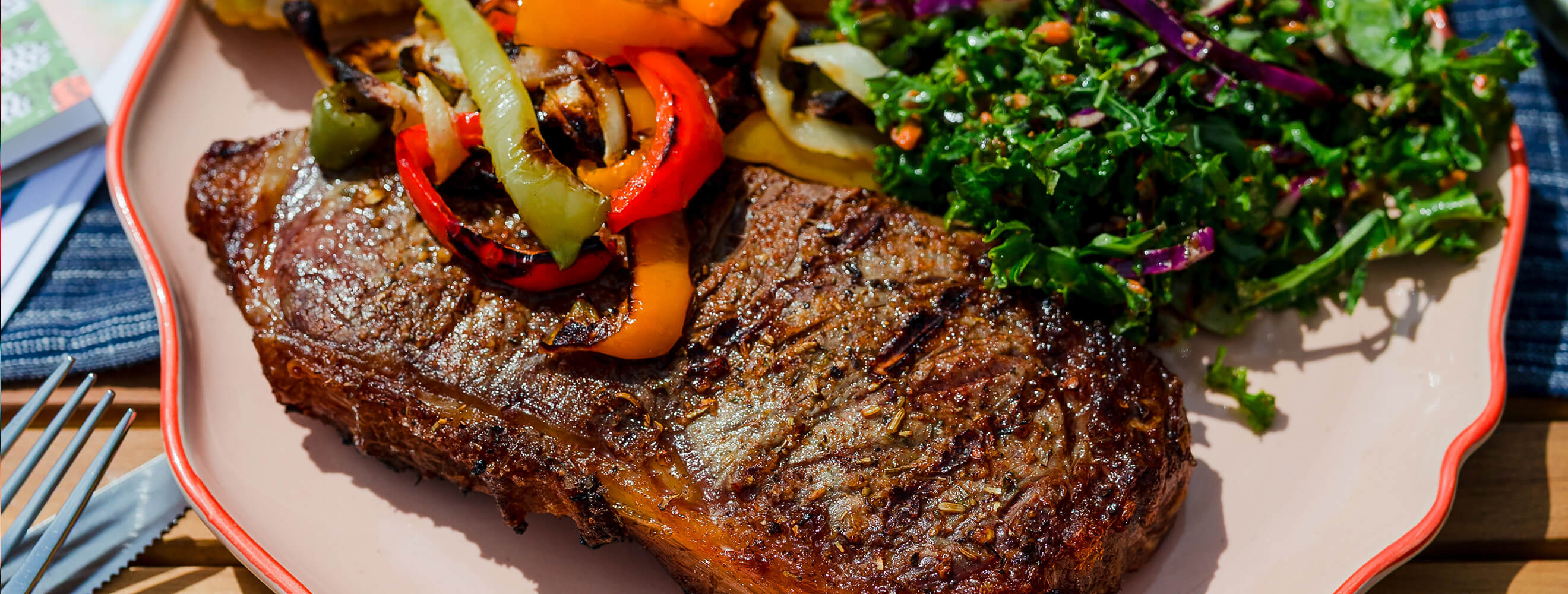 grilled steak on a plate with vegetables and greens