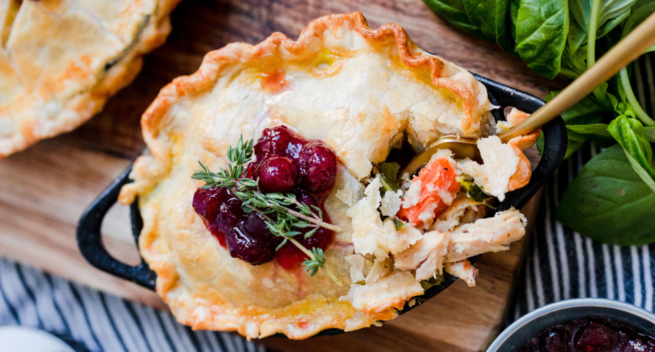 A turkey pot pie with flaky crust topped with cranberry sauce and fresh thyme. 