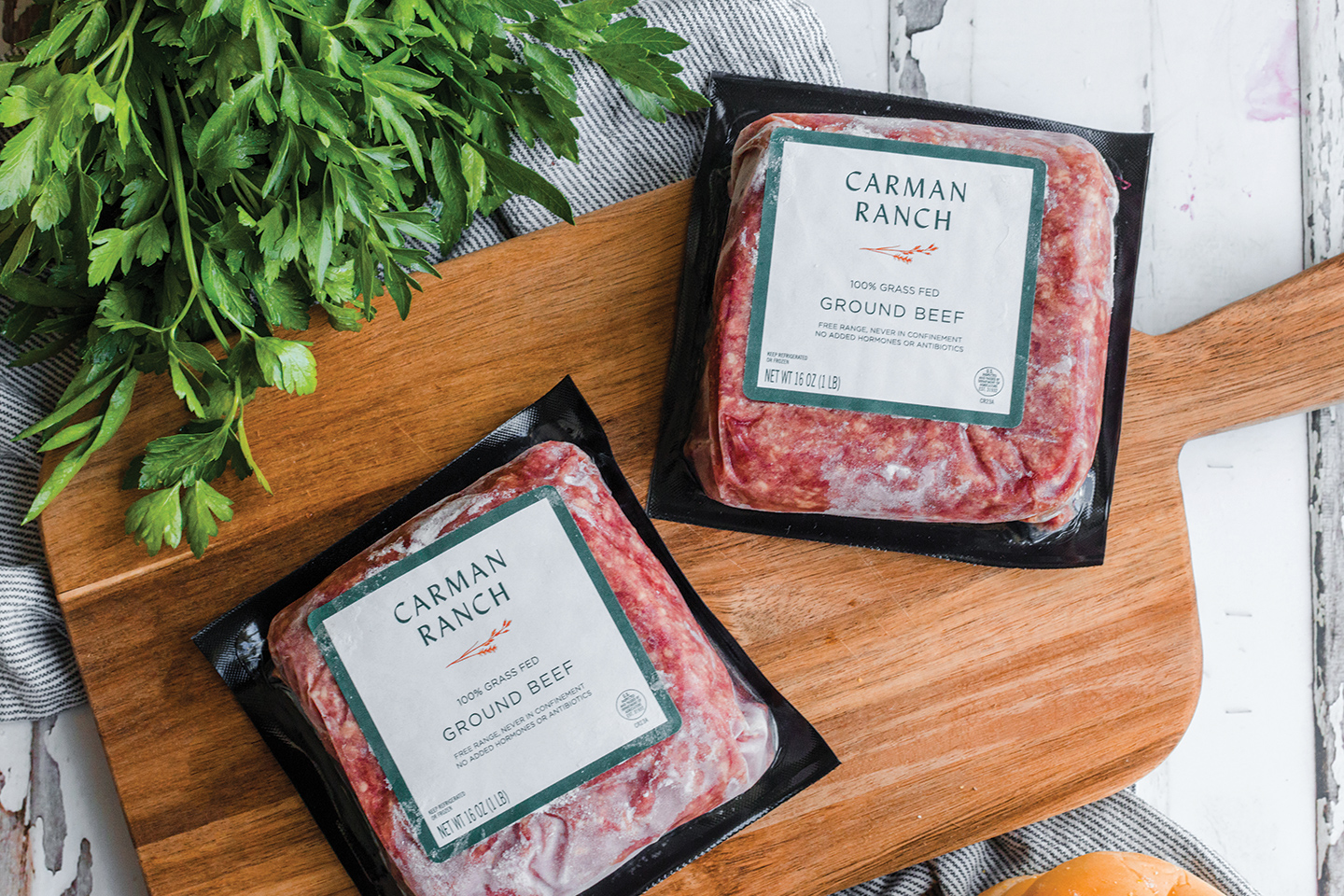 Two packs of Carman Ranch ground beef  on a cutting board