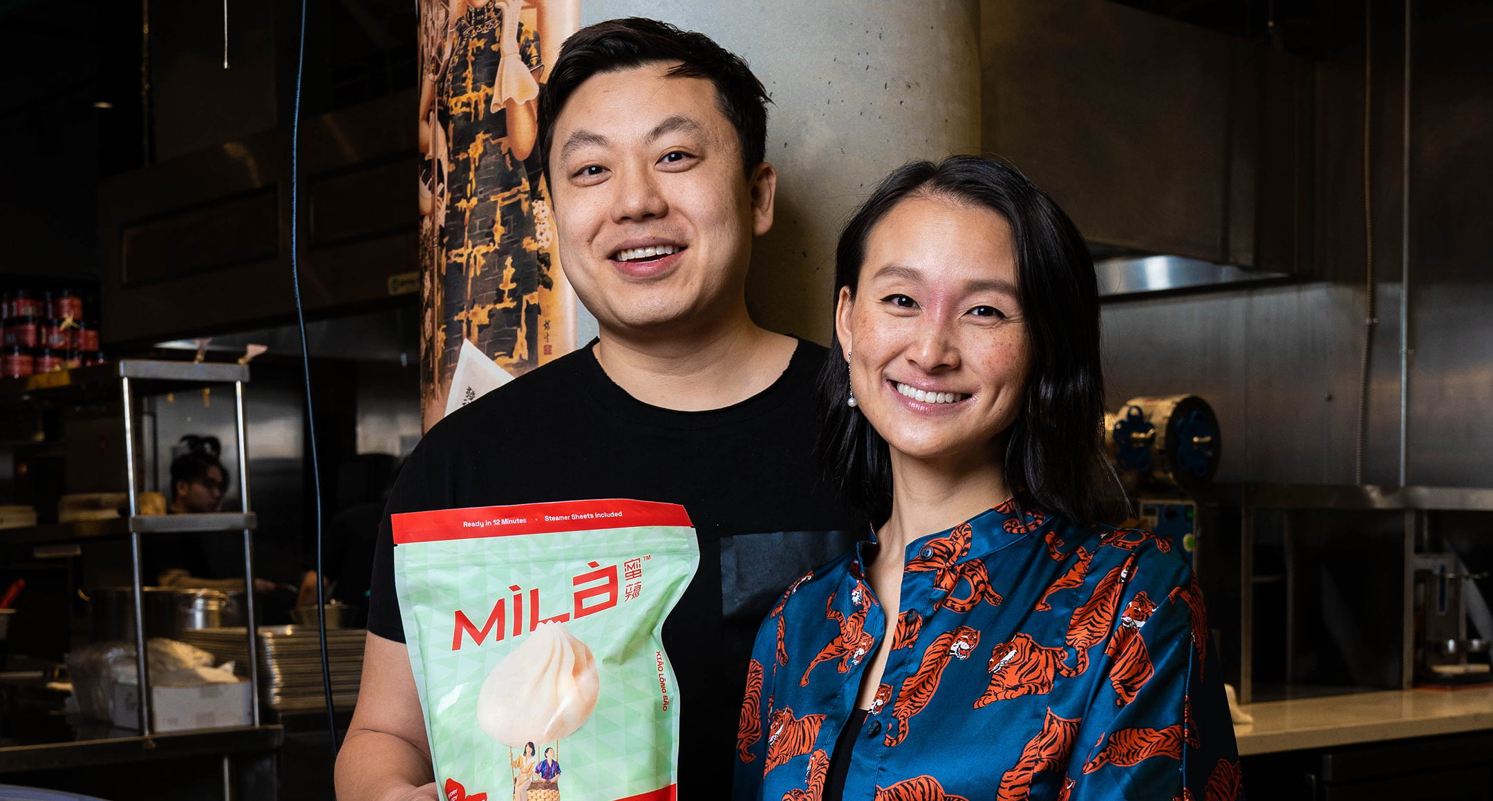 Jen and Caleb Liao standing in a kitchen holding a package from their prand MìLà.