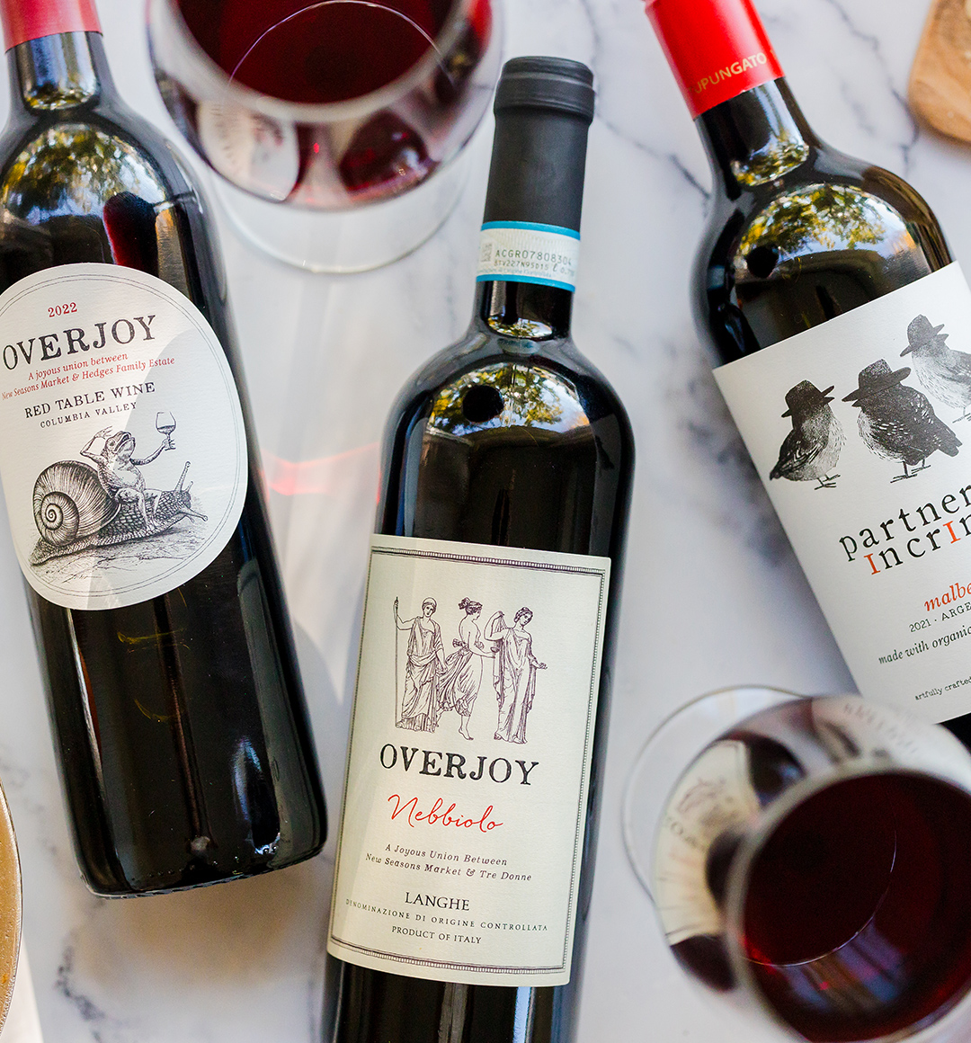 Three bottles of red wine on a tabletop from New Seasons wine partners Overjoy and Partners in Crime.