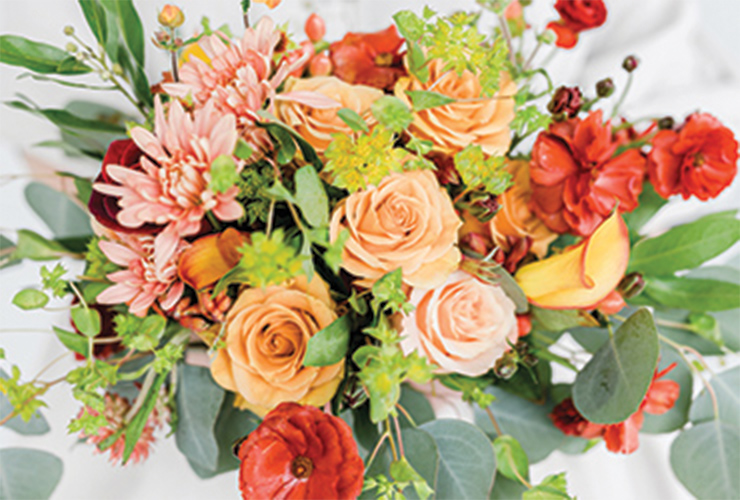A big bouquet of light, orange-colored roses, pink chrysanthemums, and leafy, green filler plants.