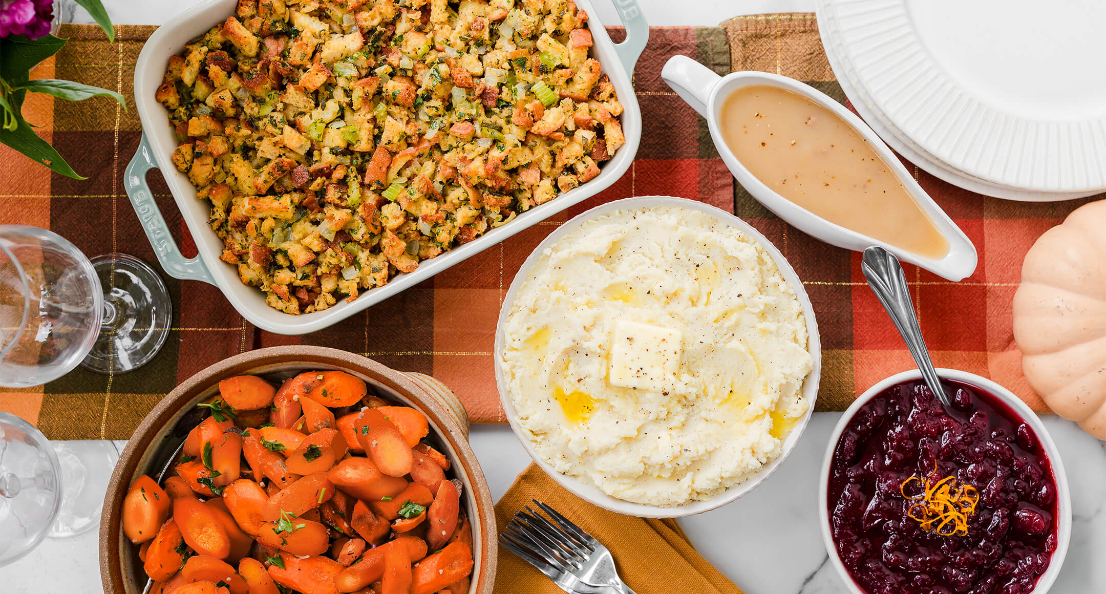 holiday sides of mashed potatoes, cranberry sauce and stuffing on a table 