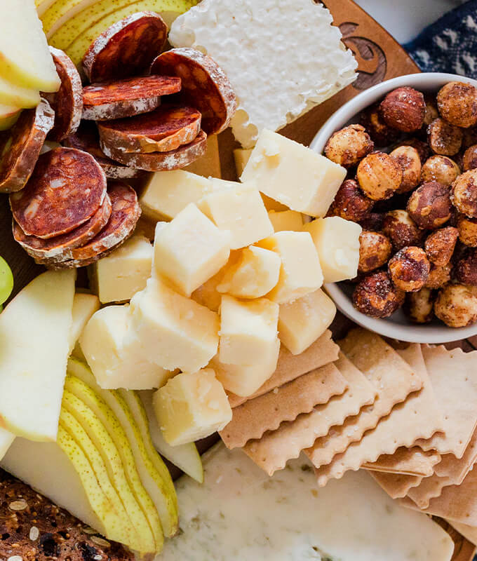 A top donw image of a variety of Oregon Cheeses with grapes, apples, assorted meats, and nuts