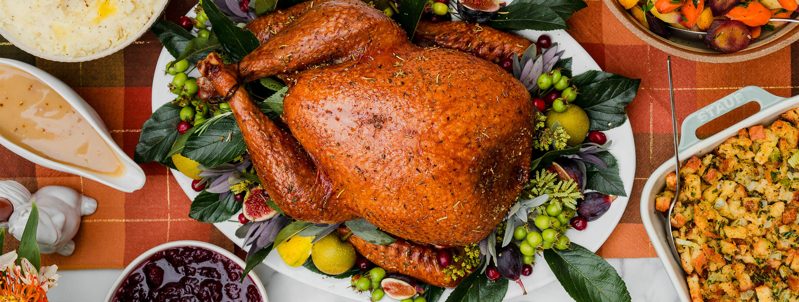 A roasted turkey on a platter with holiday side dishes.