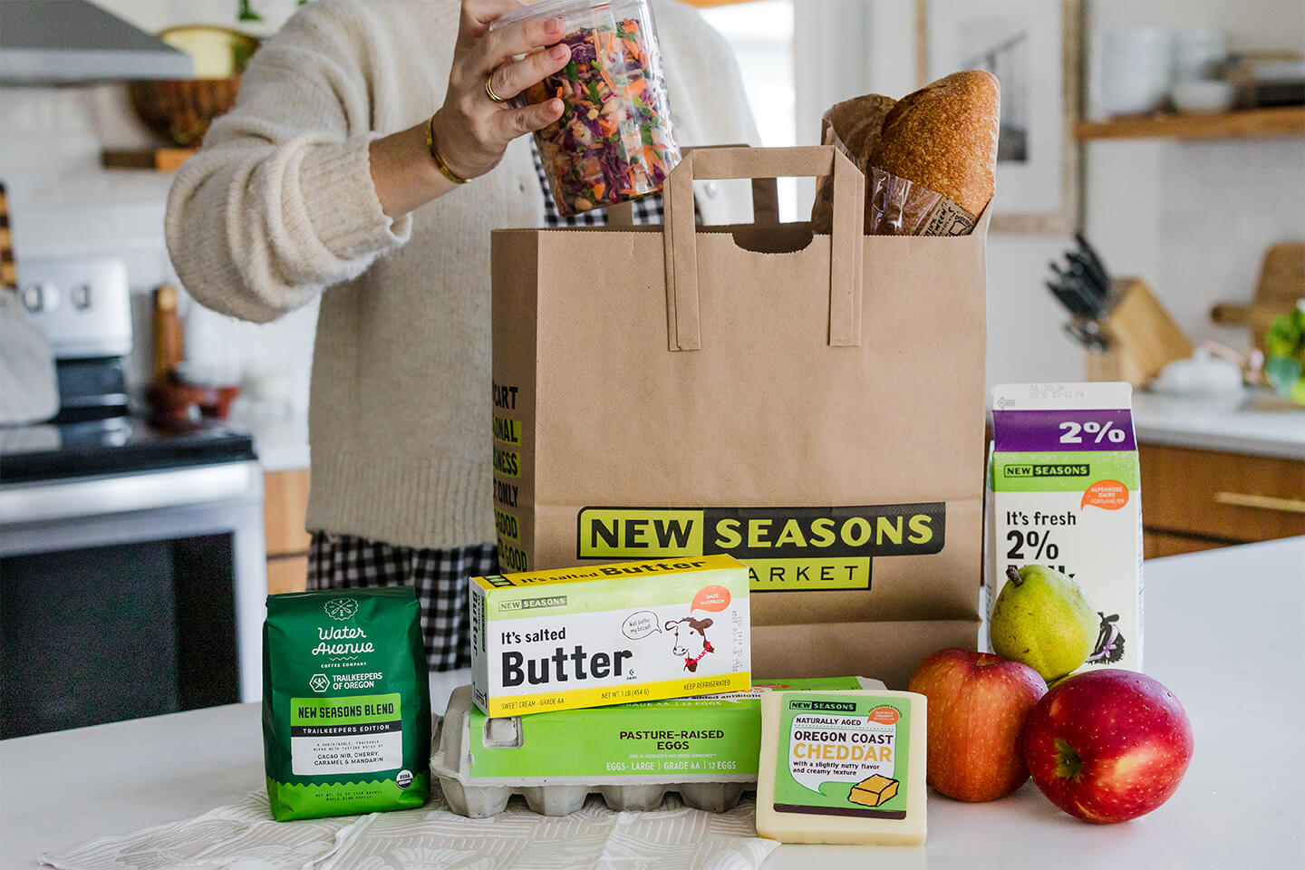 A New Seasons Market paper grocery bag surrounded by New Seasons Brand products.