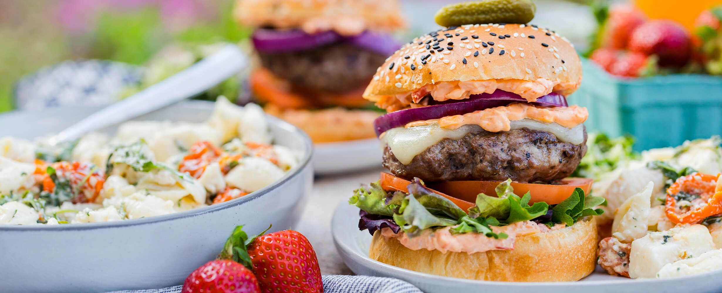 An image of a burger using 80% Lean, 20% Fat ground beef with tomatoes, lettuce, onions, and a pickle on top. 