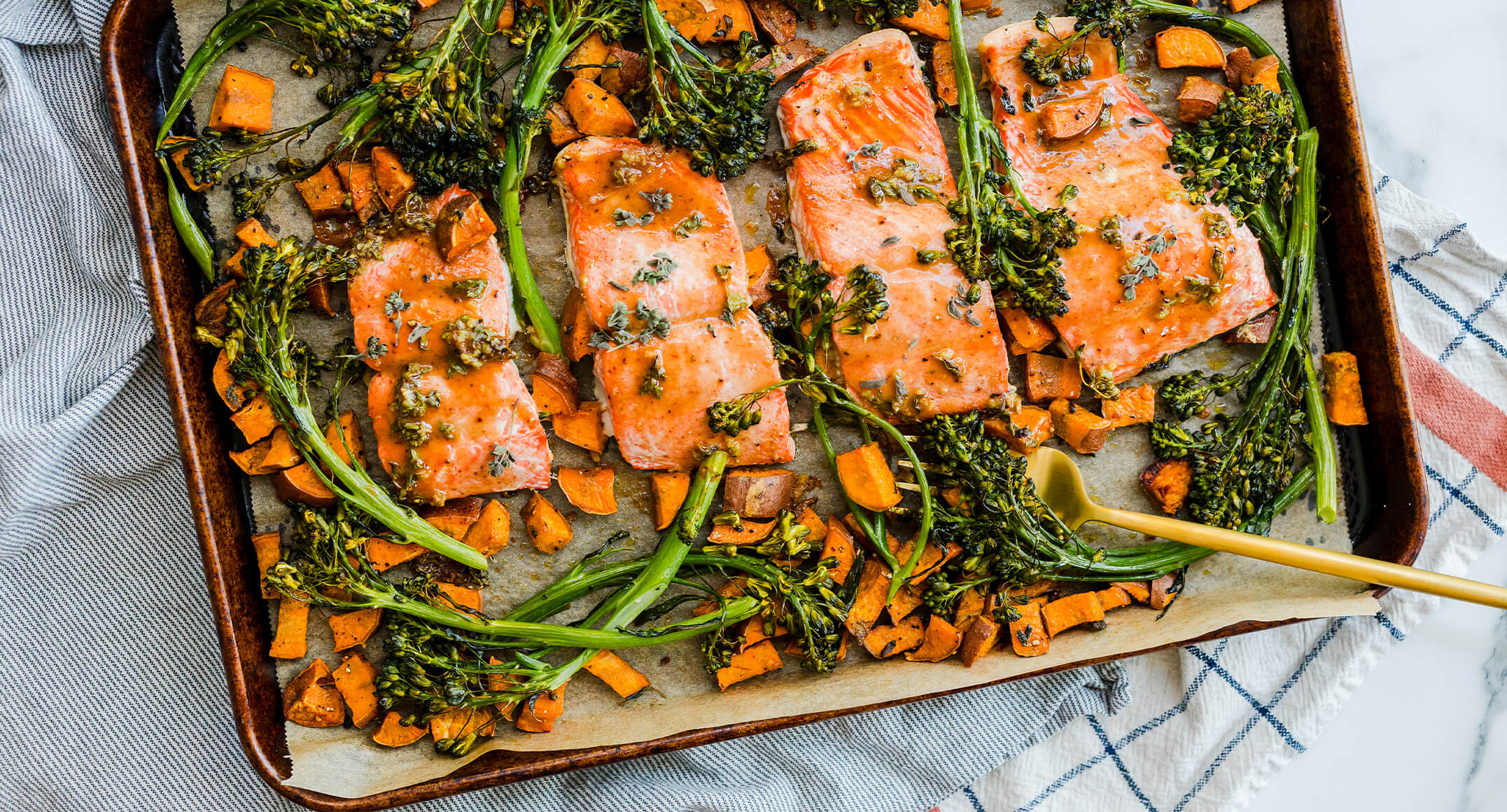 Salmon, broccolini, and sweet potatoes roasted on a sheet pan.
