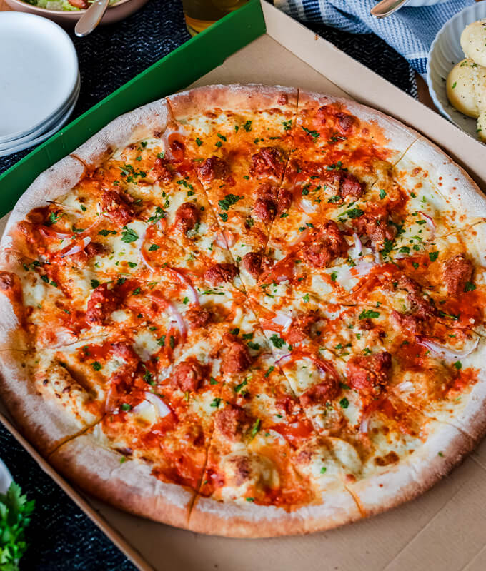 An image of a whole PizzaNW in a cardboard box. 