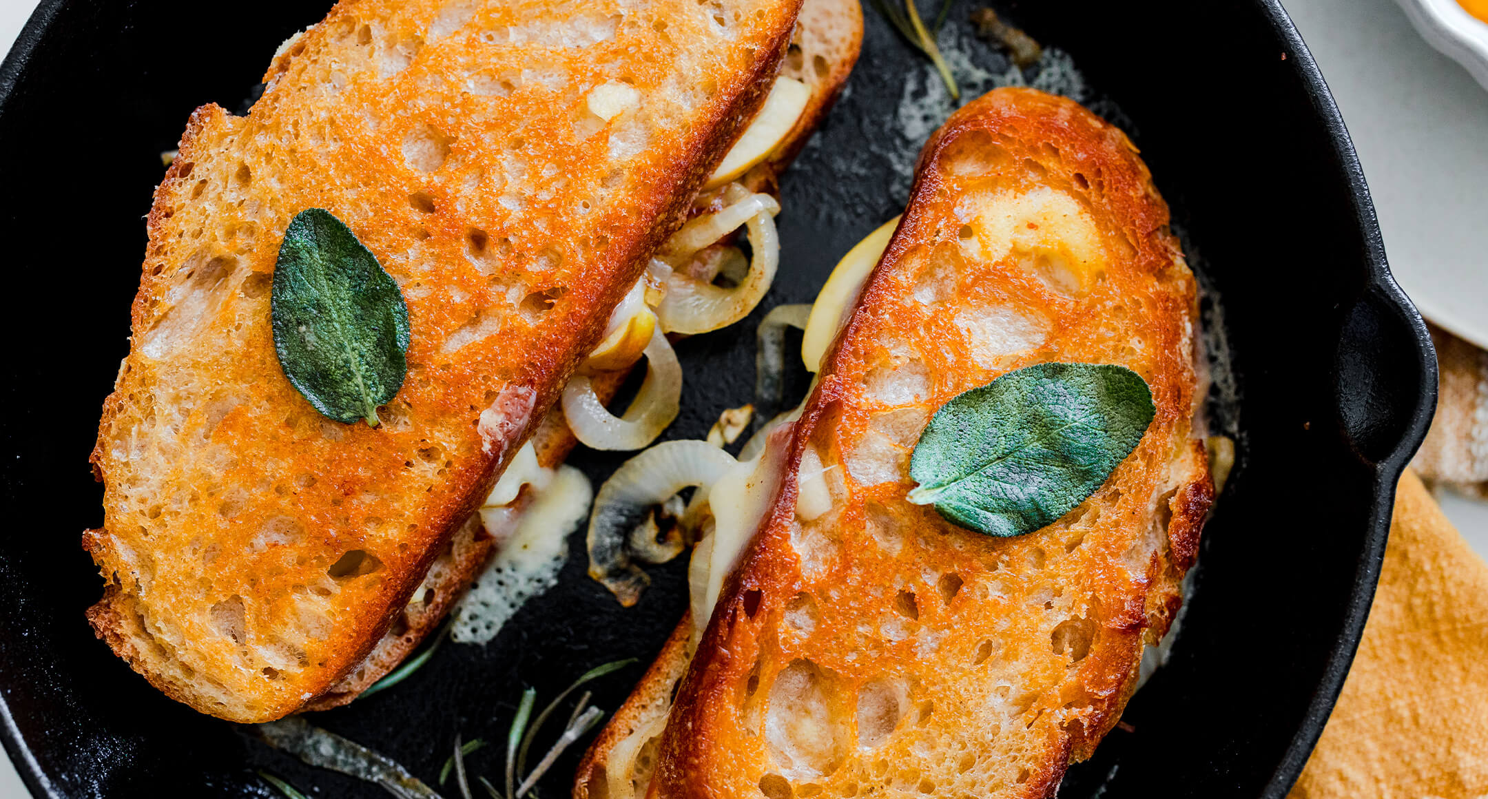 A grilled cheese with New Seasons Oregon Coast Cheddar, caramelized onion, sliced apple, and fried sage.