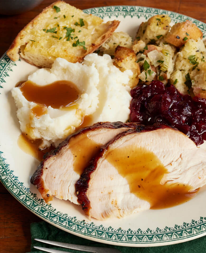 A plated Thanksgiving dinner with roasted turkey, gravy and sides.