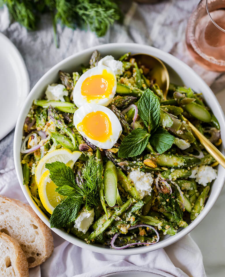 Raw asparagus salad served in a bowl with a soft-boiled egg. 