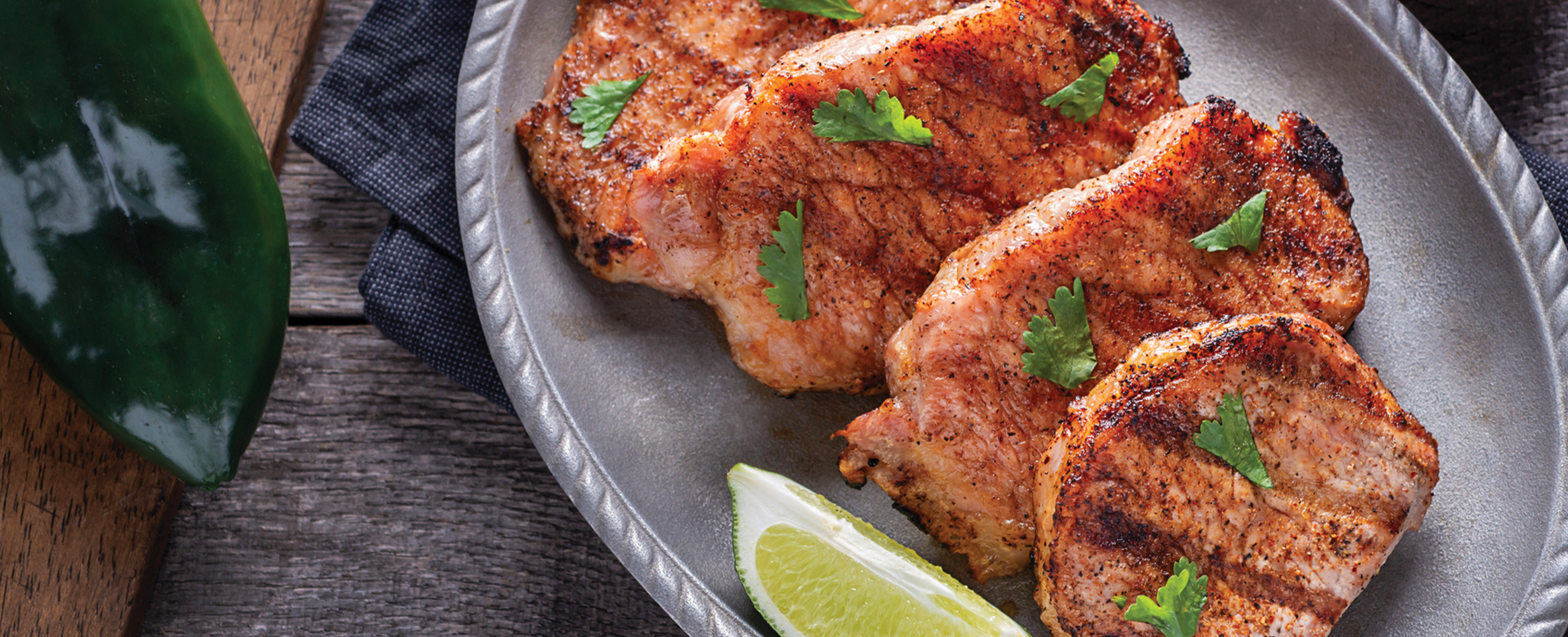 A shot of center-cut boneless pork chops on a plate with limes. 