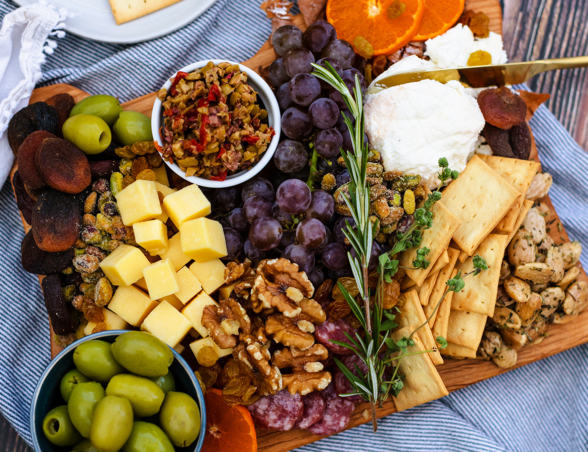 A cheese board featuring grapes, dried fruit, nuts, and local Oregon cheeses.