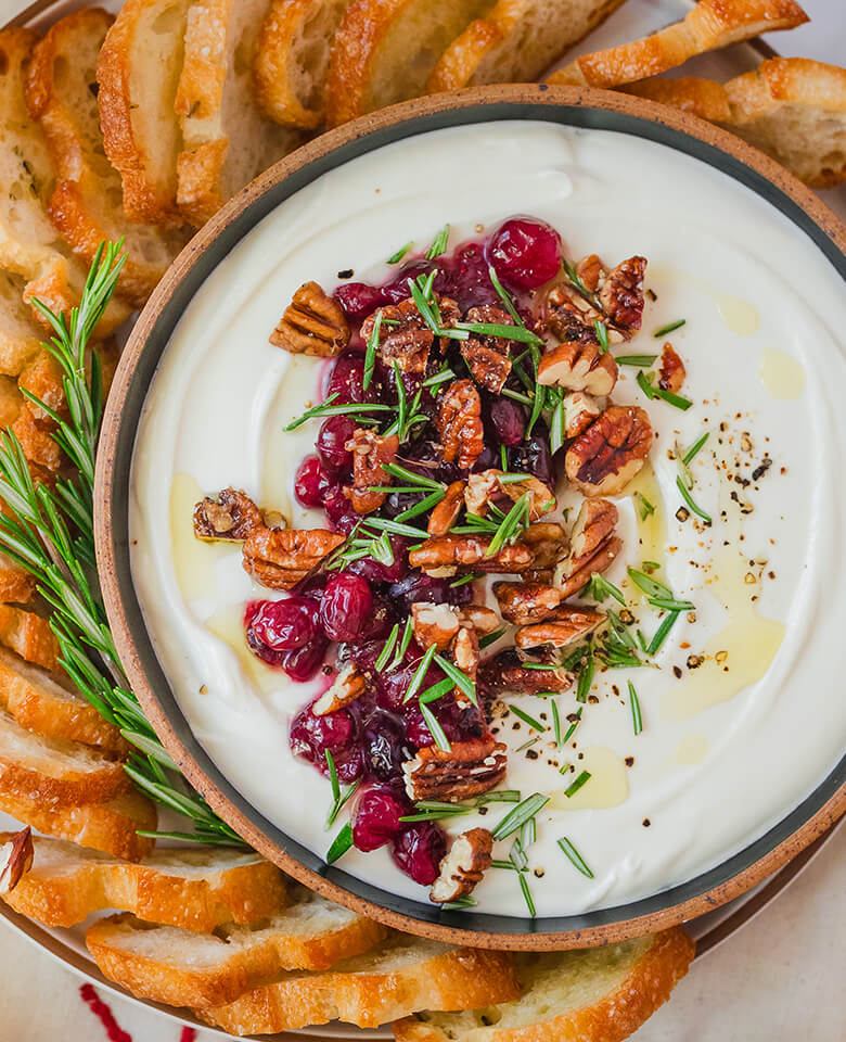 Cranberries and rosemary pecans served with whipped feta on a plate.