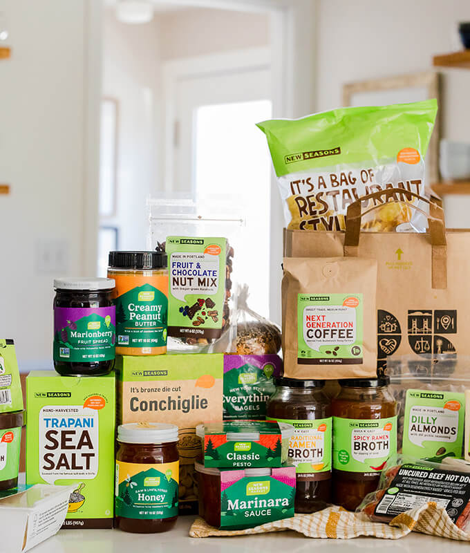 New Seasons branded packaged grocery items on a kitchen counter including pasta, ice cream, salt, nut butters, chips and more.