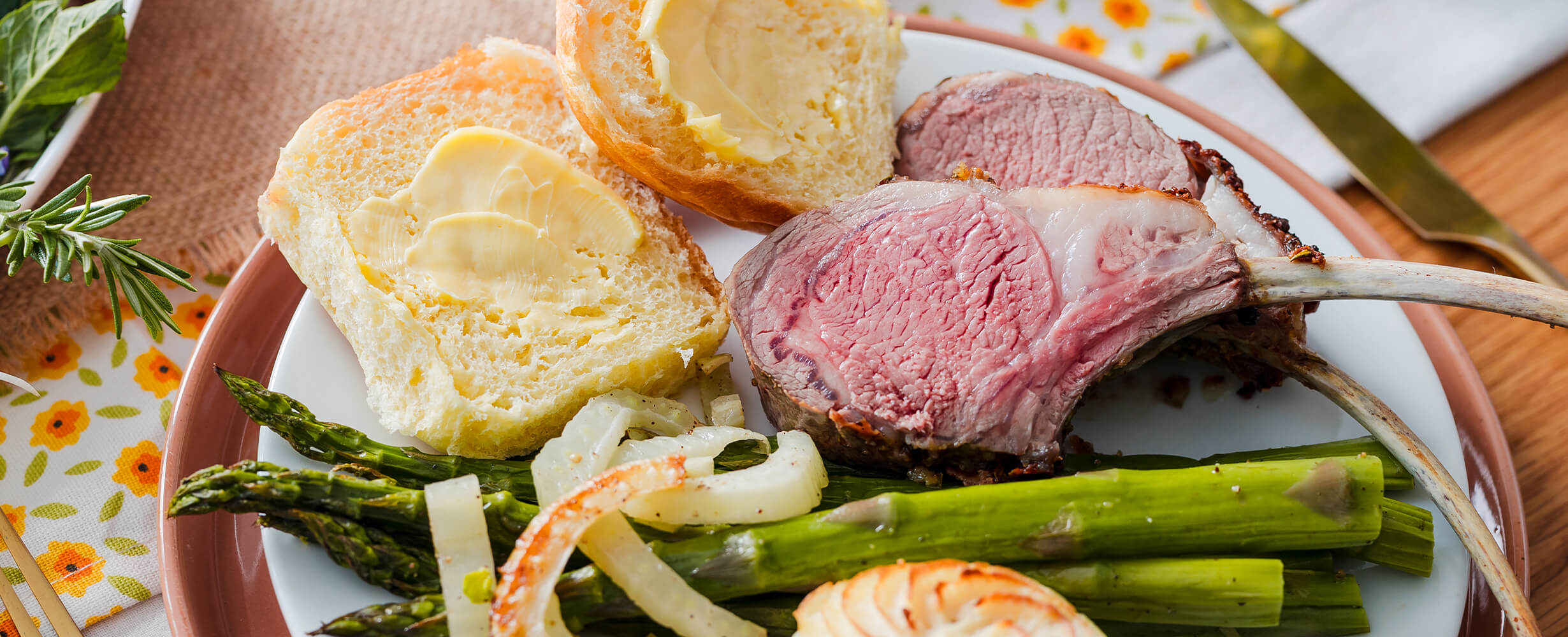 A plate of food including bread, lamb, asparagus, and onion.
