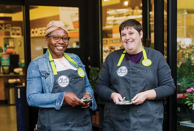 Two people standing next to one another wearing New Seasons aprons and smiling. 