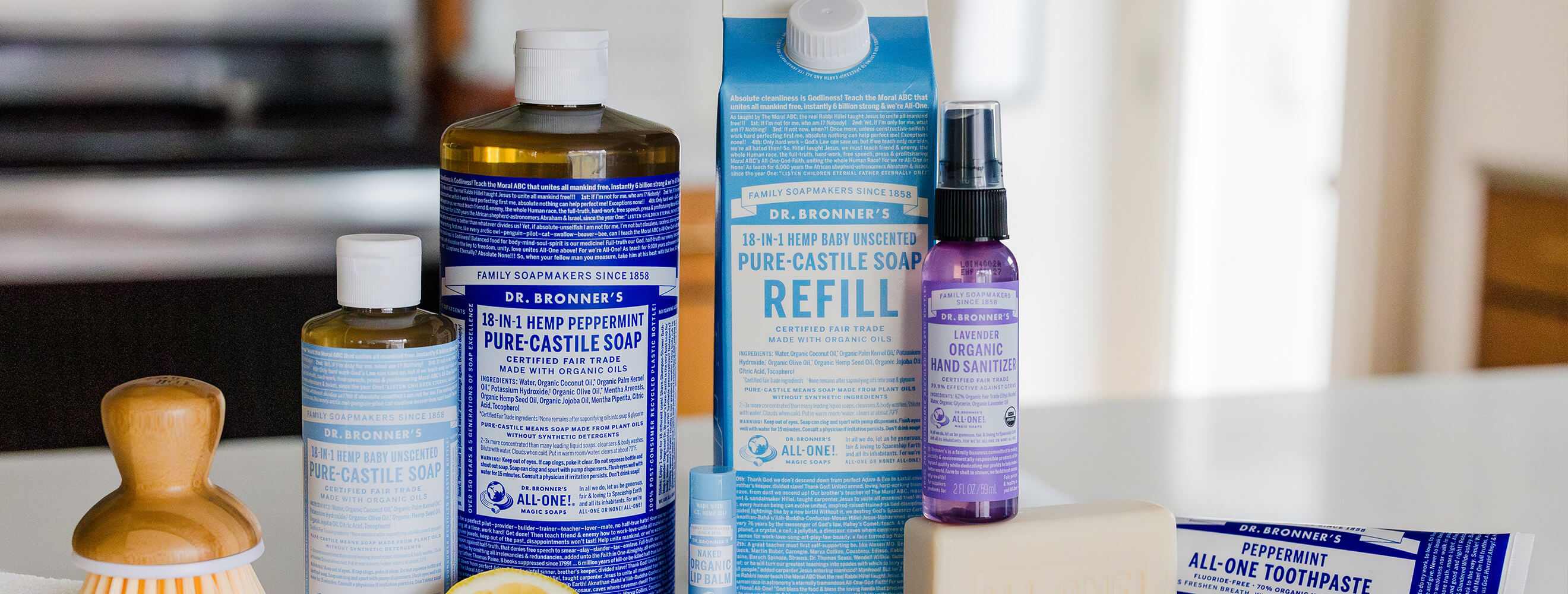 Dr. Bronner's products on a counter like castile soap, hand sanitizer, and toothpaste.
