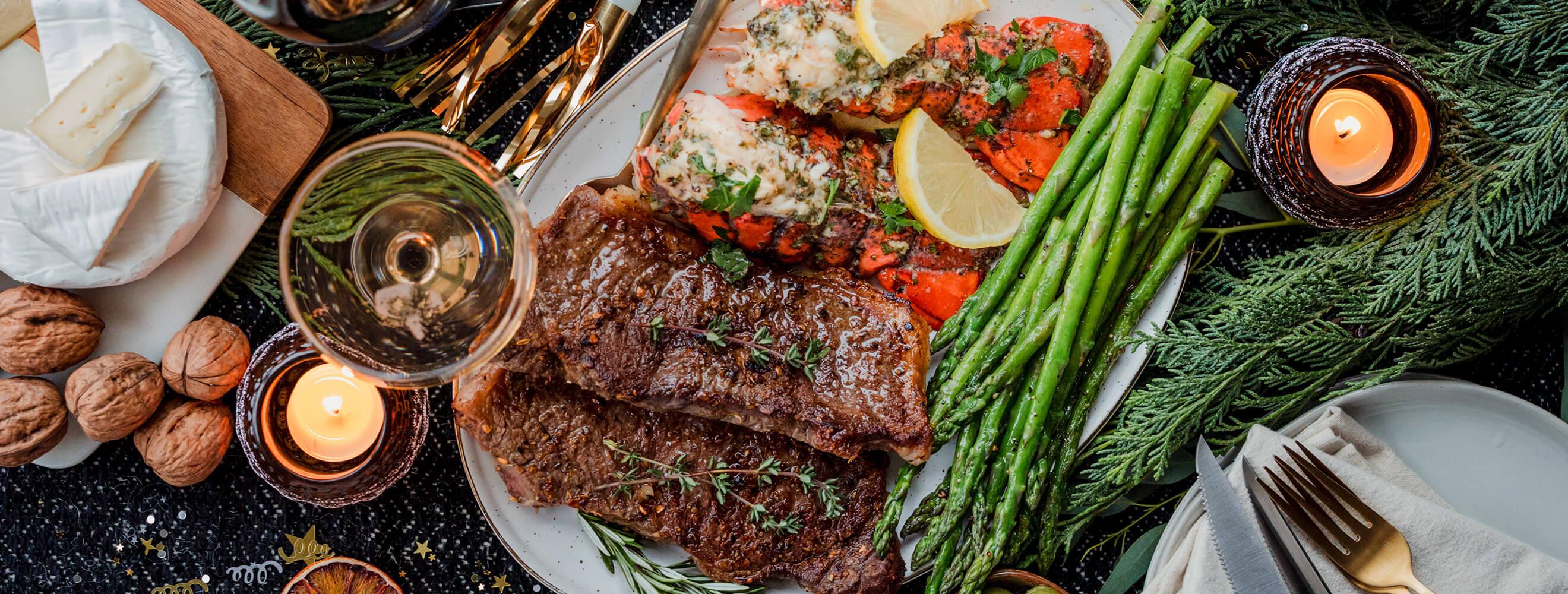 a meal of cooked steak, lobster and green beans in a festive table scene