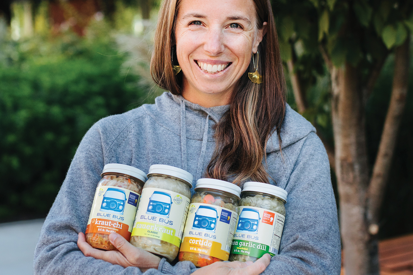 woman in sweatshirt holding 4 jars of condiments