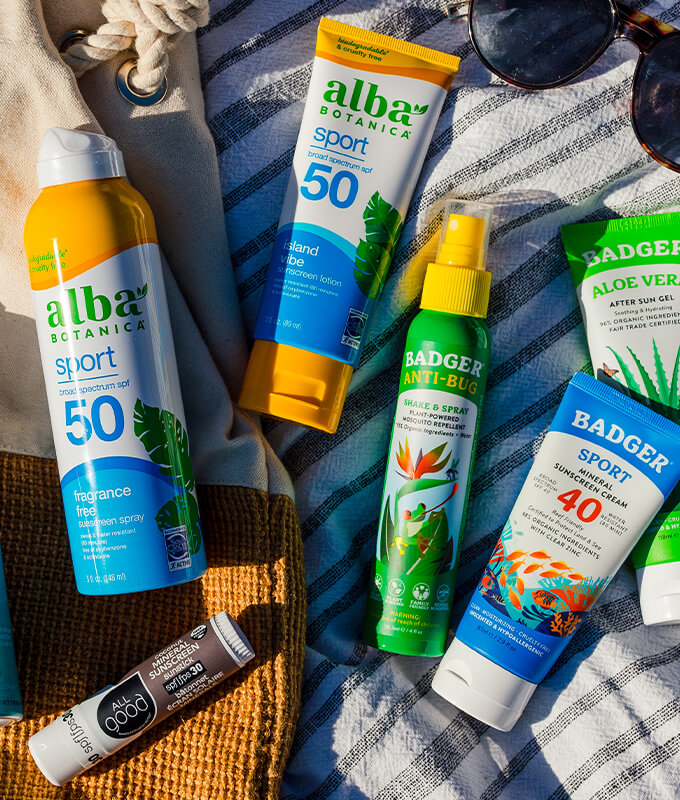 A collection of summer wellness products including sunscreen, bug spray, and aloe vera gel.