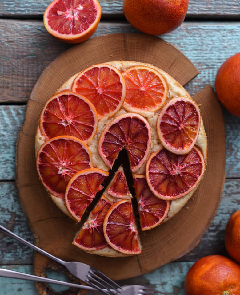 blood orange cake presented on a round wooden board 