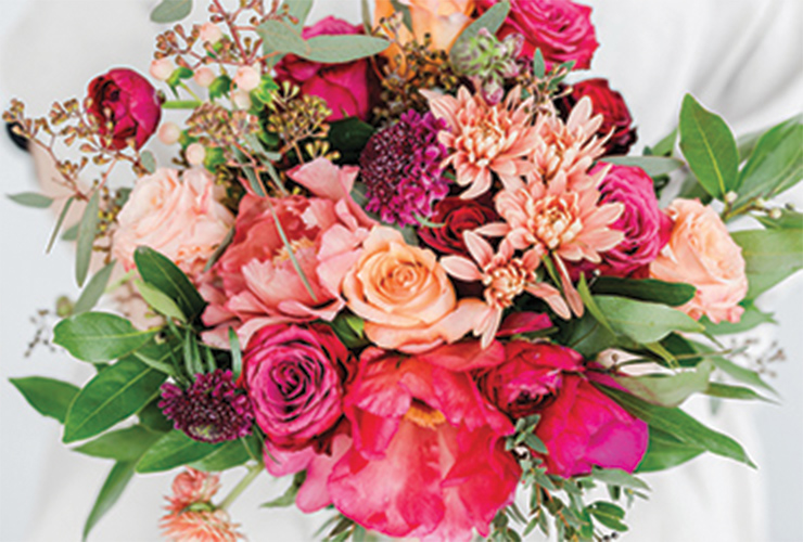 A bouquet of several different types of bright magenta and pastel, peach-colored flowers.