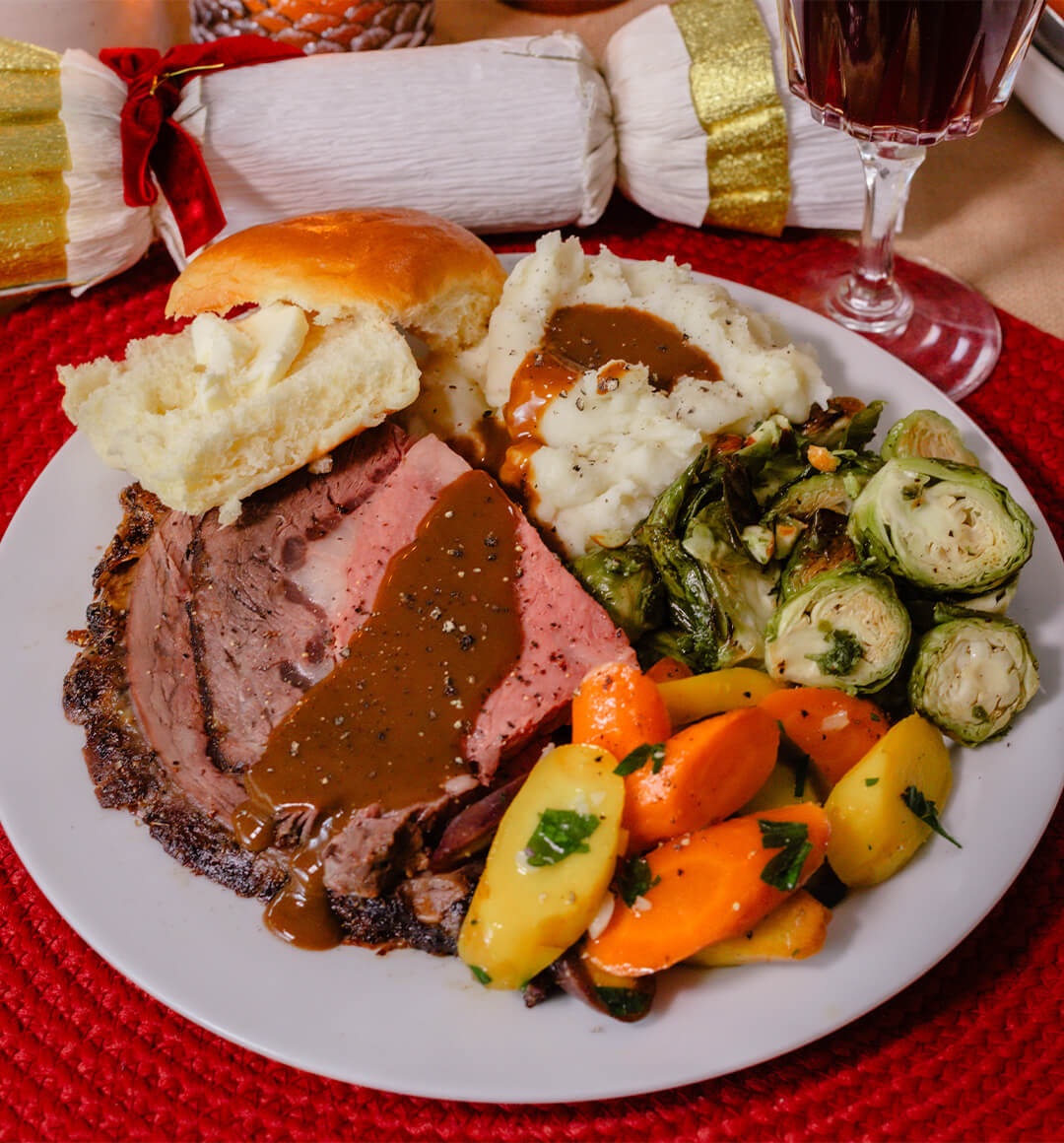 A dinner plate with rib roast, mashed potatoes, brussel sprouts and carrots