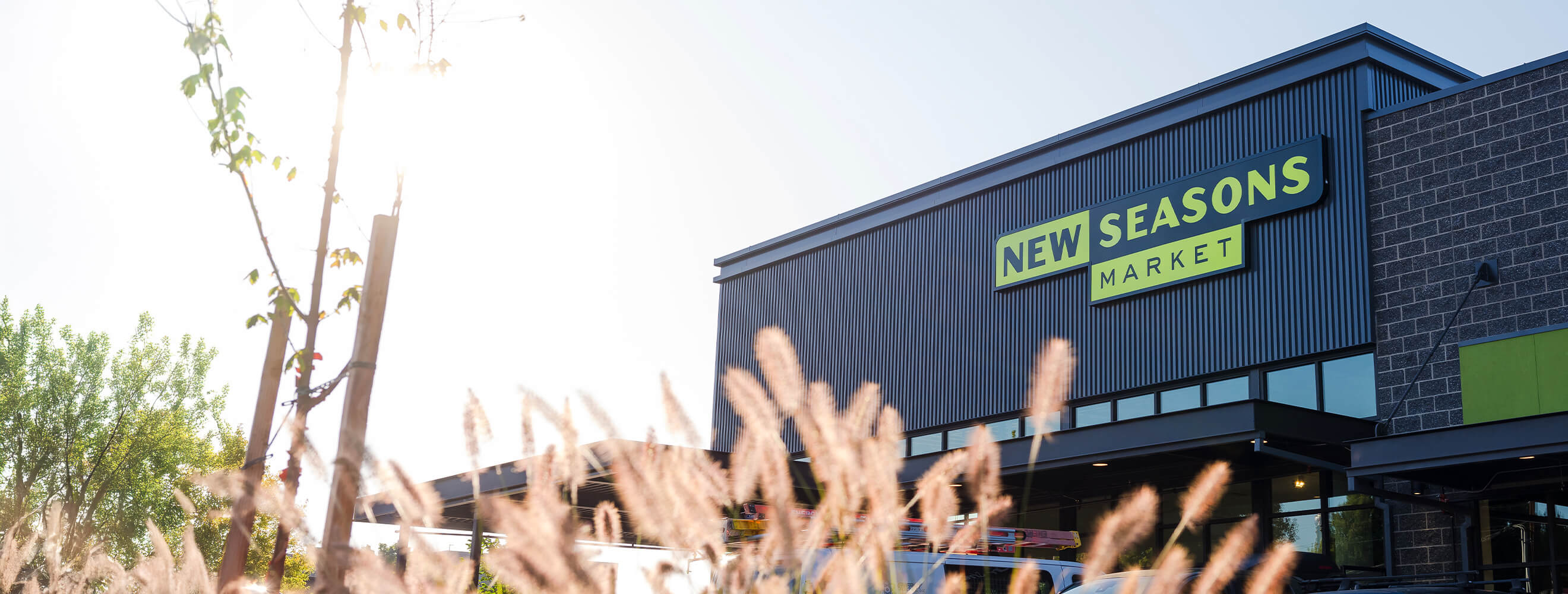 exterior shot of a New Seasons Market grocery store with some plants in the forefront.