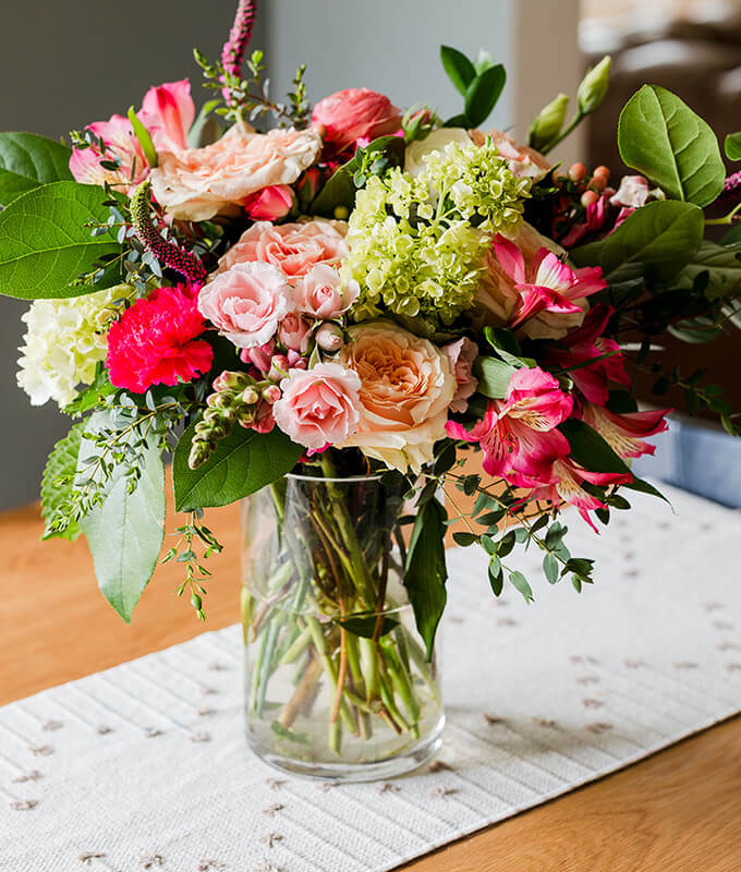 a beautiful fresh bouquet of flowers in a clear vase with water on a table