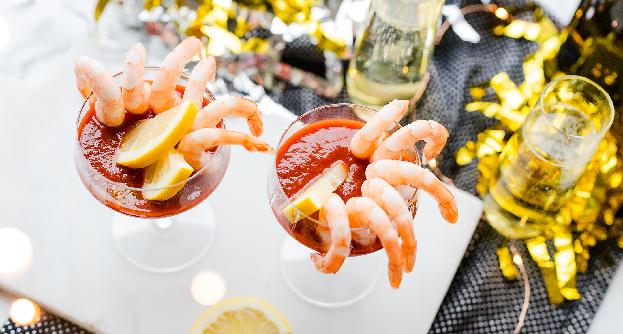 A shrimp cocktail appetizer with ready-to-eat shrimp lining a glass filled with cocktail sauce.