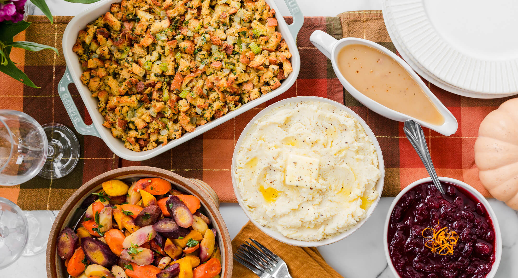 holiday sides of mashed potatoes, cranberry sauce and stuffing on a table 