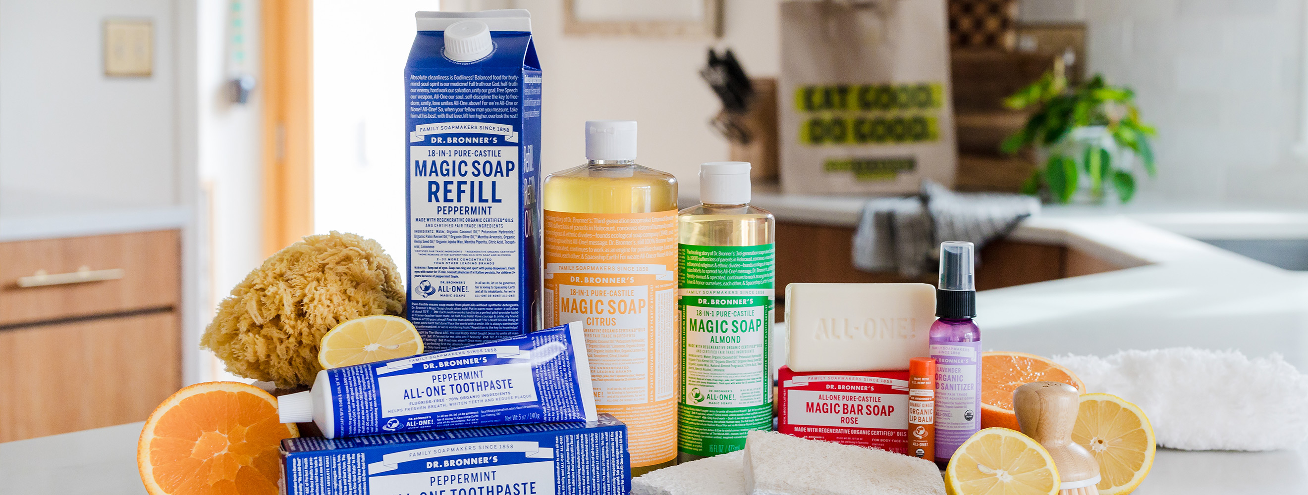 A straight on shot of an assortment of Dr. Bronner's products including Peppermint all-one toothpaste; magic soap refill; magic soap citrus; magic soap almond; magic bar soap; and organic lip balm.