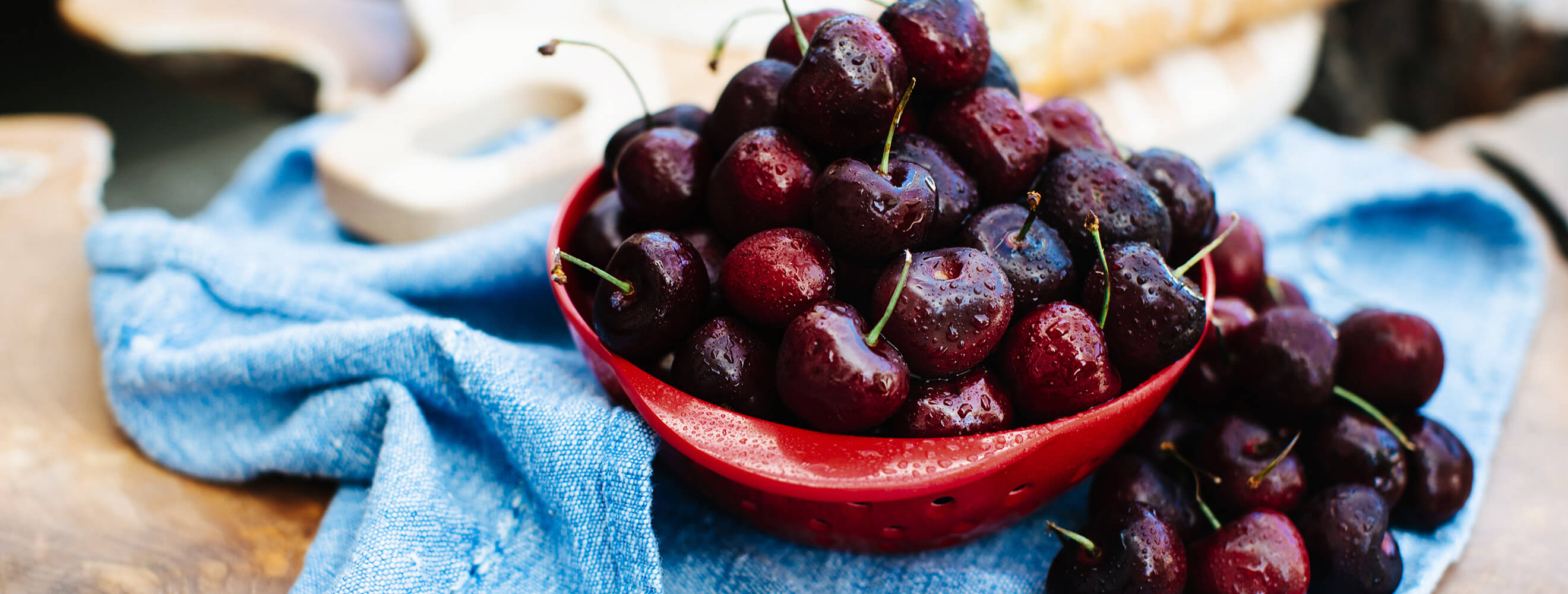 a bowl of fresh cherries on a blue towel