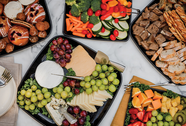 platters of fresh fruit, fresh veggies, and charcuterie arranged on a marble surface