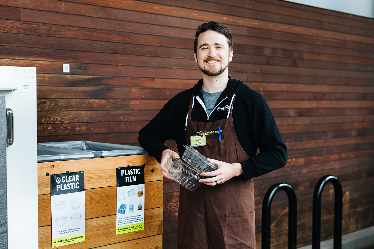 New Seasons Staff member with #1 plastics in front of recycling center 