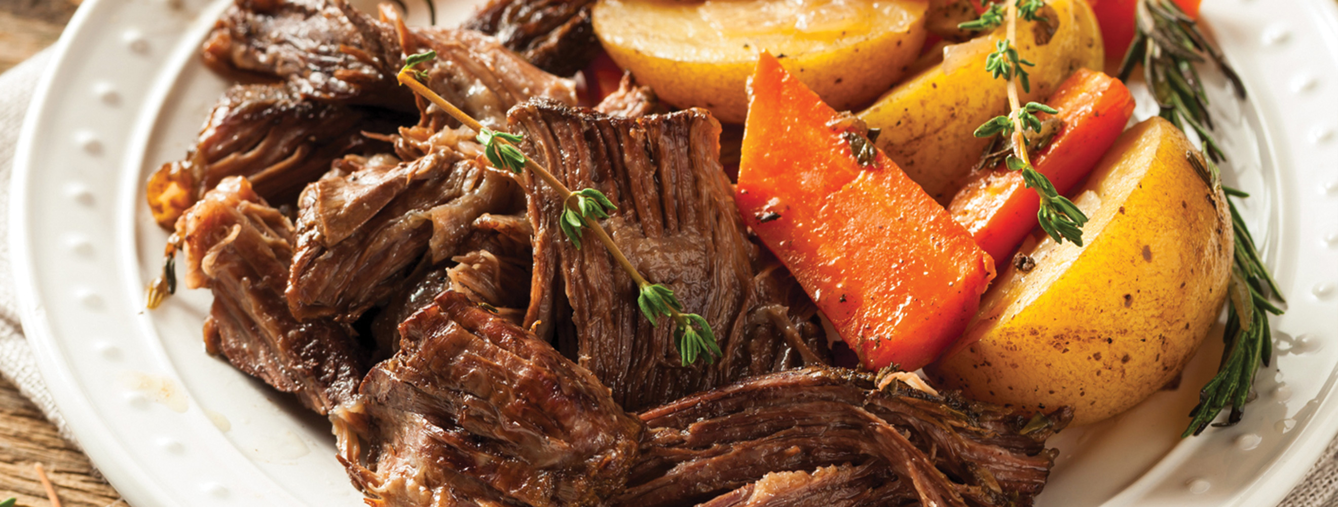 Beef stew with carrots and potatoes in a white bowl.