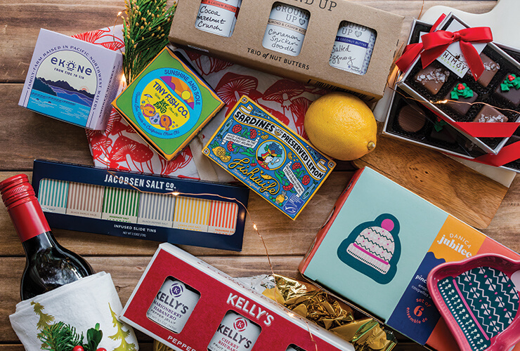 Gift items like a bottle of wine, salts, hand soap, and chocolates arranged on a flat surface.