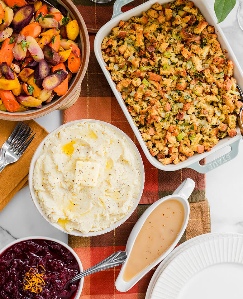 Holiday sides of mashed potatoes, cranberry sauce and stuffing on a table