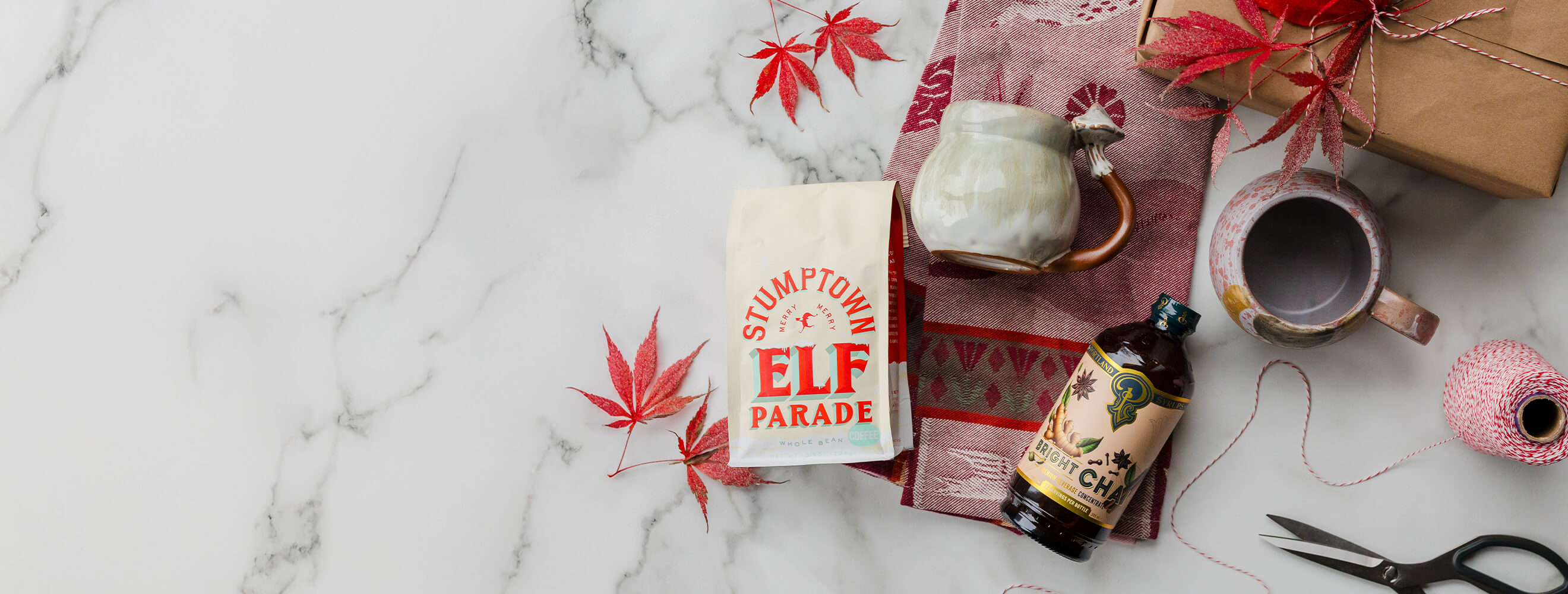 A variety of gifts such as ceramic mugs, seasonal coffee, dish towels and syrups.