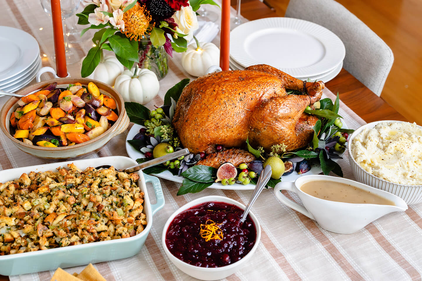 A table spread of turkey, mashed potatoes, cranberry sauce, gravy, carrots and stuffing.