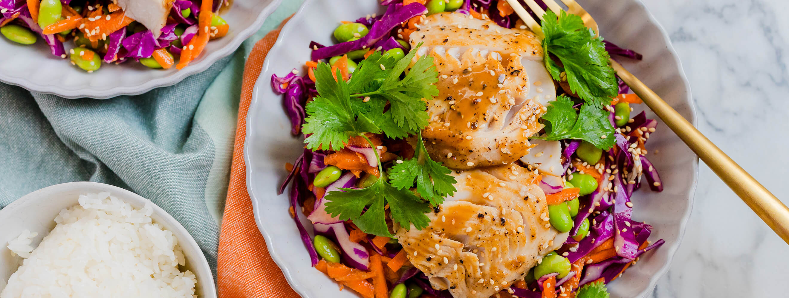 cooked white fish with a glaze over a bed of shredded red cabbage and carrots with cilantro