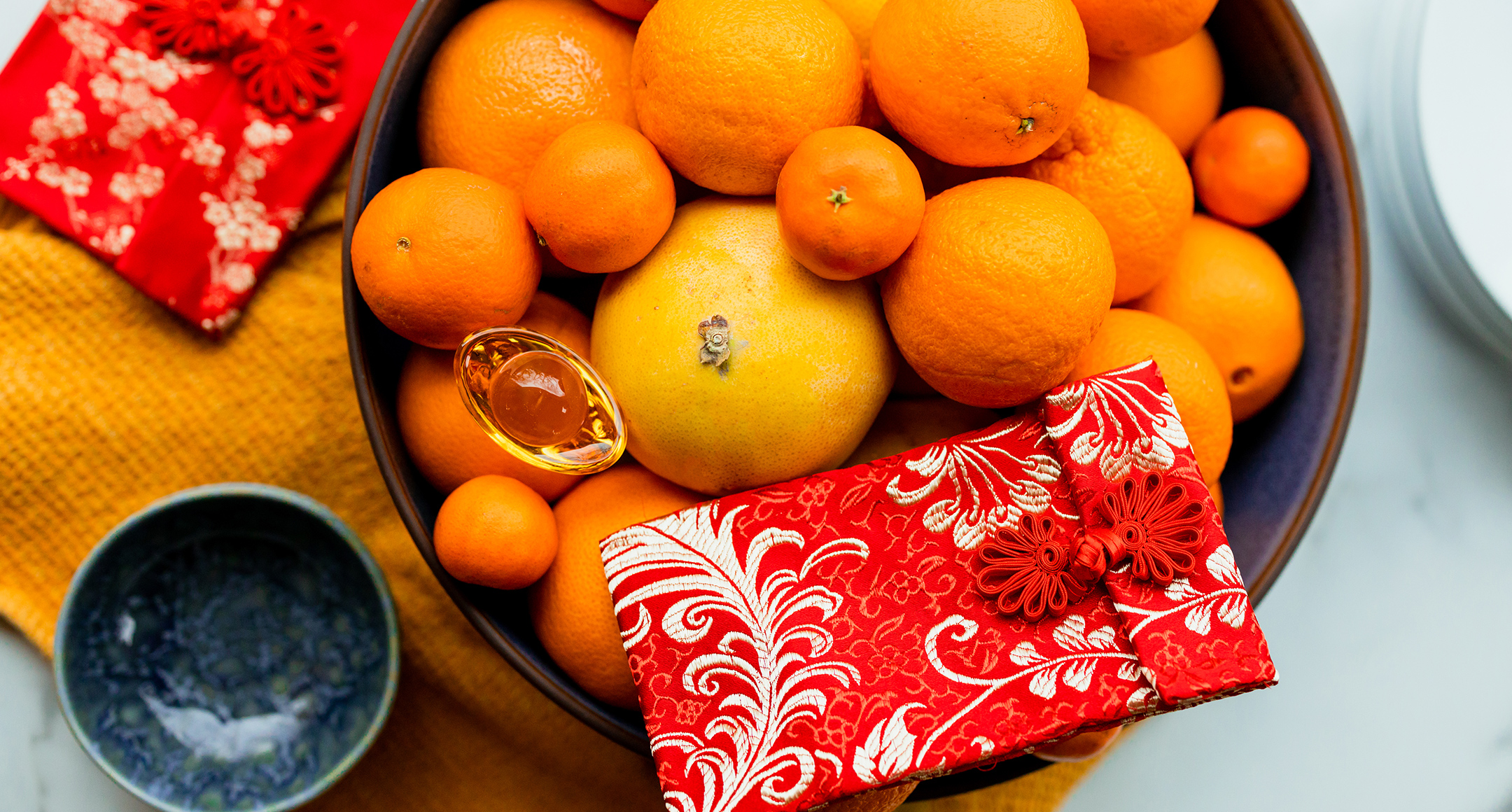 A bowl of vibrant orange citrus fruits and lucky red envelopes symbolize Lunar New Year. 