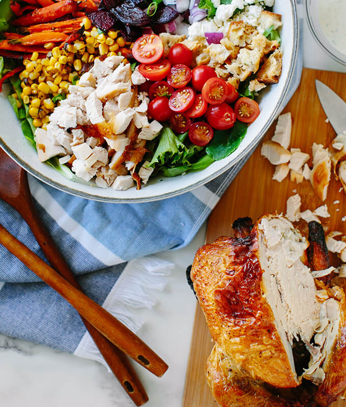 salad bowl with fresh vegetables and a cut up rotisserie chicken on the side.