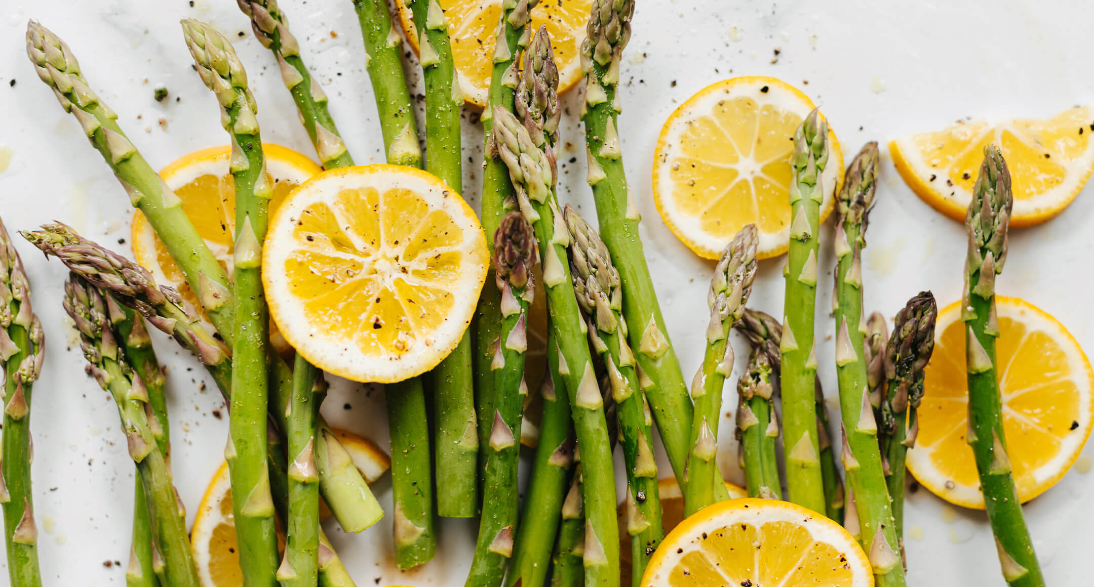 Asparagus spears laid out on a surface with lemon slices arranged throughout.