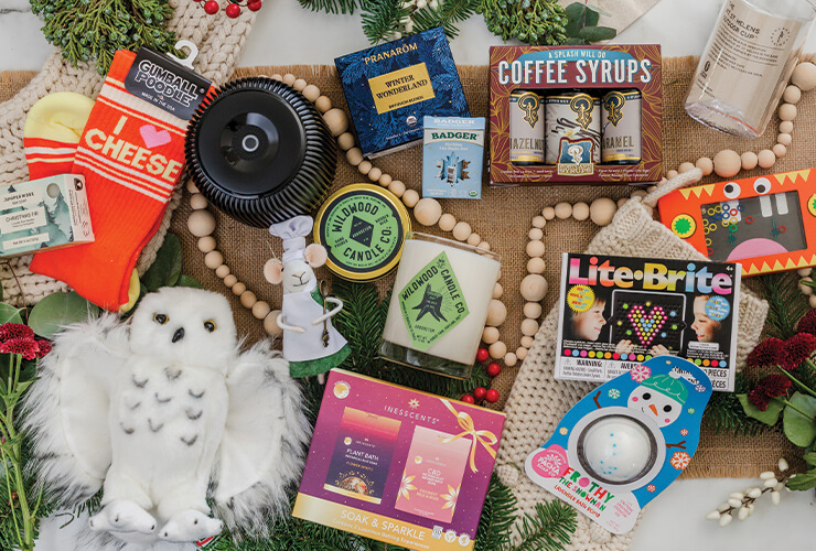 Gift items like a stuffed animal, candle, hand soap, coffee, and travel mug arranged on a flat surface.