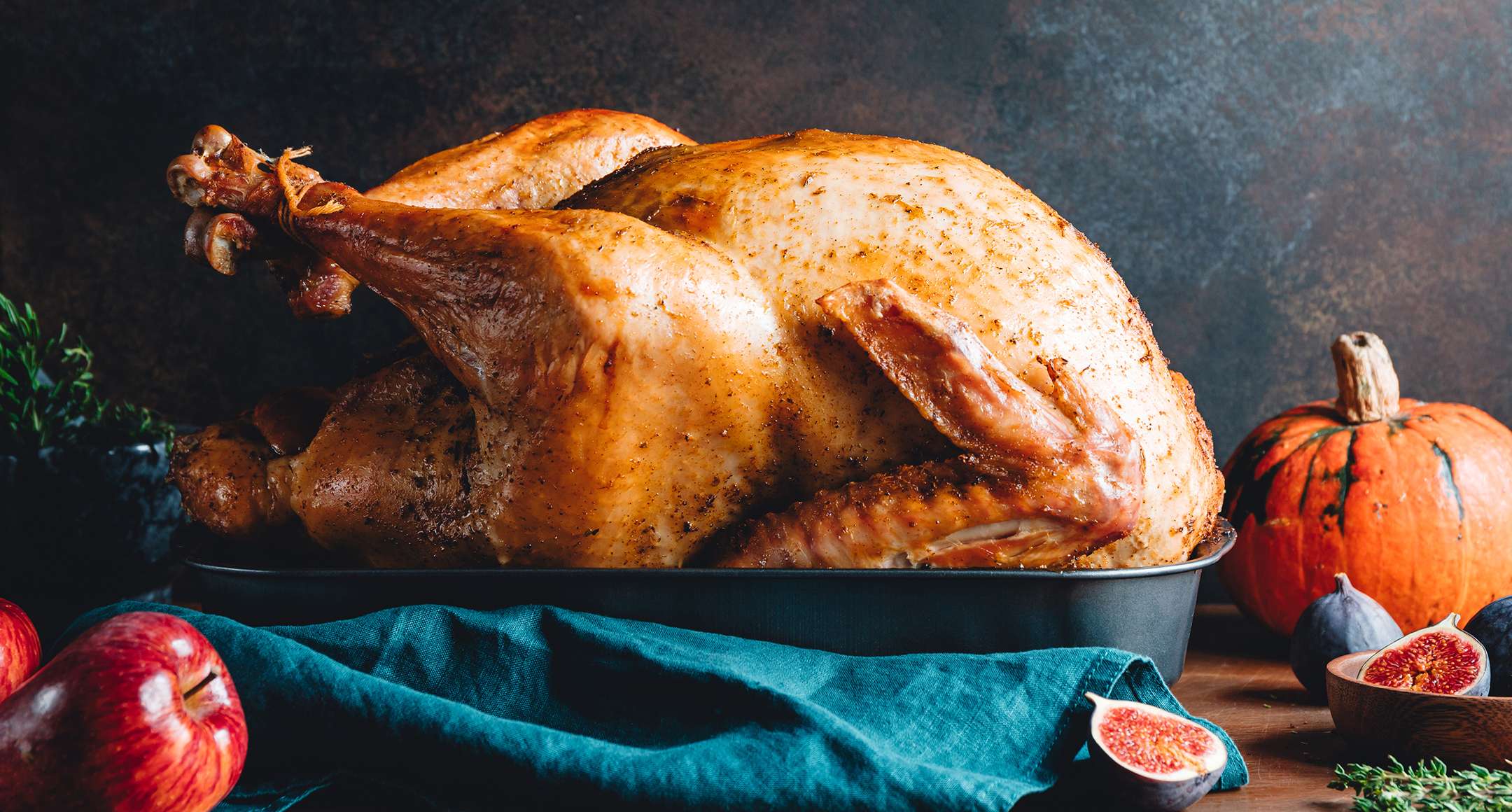 A whole dry-brined turkey on a roasting pan ready for the oven.