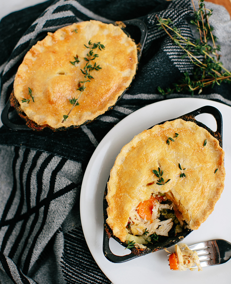 A perfectly baked chicken pot pie with a golden-brown crust topped with fresh thyme.
